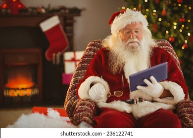 Santa Holding His Glasses And Using Tablet At Home In The Living Room