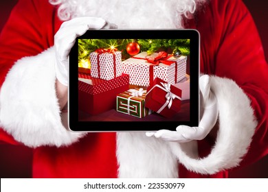 Santa Holding A Tablet With Photo Of Christmas Presents