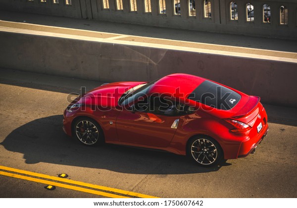 Santa Monica Beach, year\
2018: rear top view of a red Nissan 370 Z driving on a coastal\
street.