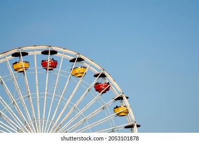 Santa Monica, USA - September 8, 2010:  Part Of A Large White Ferris Wheel At The Funfair, With Red And Yellow Gondolas Against A Blue Sky.