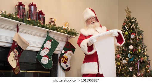 Santa Reading His Naughty Or Nice List In A Living Room Decorated For Christmas.