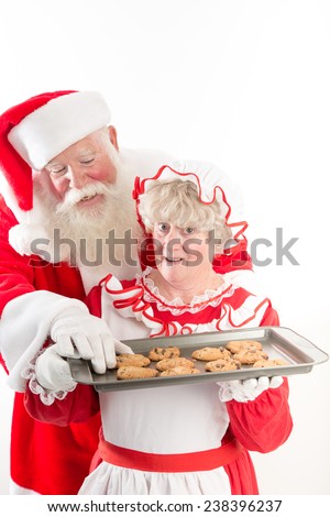Santa steals a warm cookie from Mrs Claus tray.