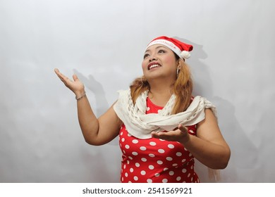 Santa woman showing copy space standing in red Santa hat. Isolated on white background. Asian woman smiling. - Powered by Shutterstock