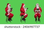 Santa working on digital tablet during christmas eve holiday, expressing december seasonal event. Young man saint nick sitting on chair against full body greenscreen backdrop, using gadget.