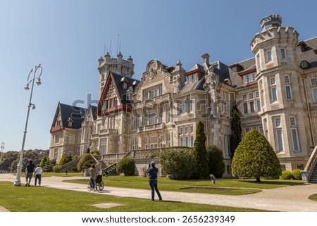 Santander, Spain. Spring view of the Palacio de la Magdalena with its grand facade, lush green lawn, and clear blue sky, once the royal summer residence of the Spanish monarchy