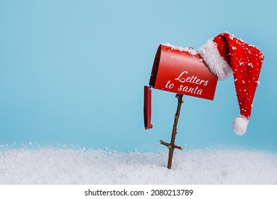 Santa's red mailbox with snow isolated on bright blue background. Letters to Santa with Xmas wishes. Creative New Year and Christmas concept. Minimal winter December holiday banner with copy space.