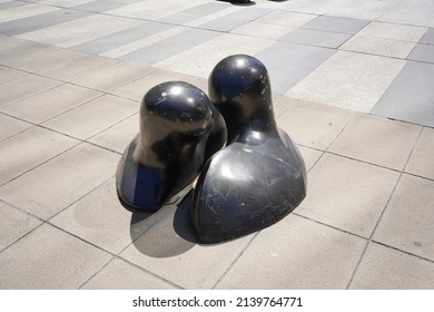 Santiago - Chile - February 10, 2022: modern black statues representing faces of two persons kissing on the ground (modern public square in front of Costanera center).