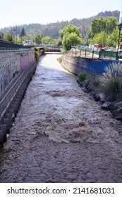 Santiago - Chile - February 10, 2022: view of brown dirty running water in a canal San Carlos close to the Costanera center  