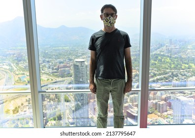 Santiago - Chile - March 05, 2022 - portrait of a young tourist male at the top of the Costanera center tower in front of Santiago view during sunny day. 