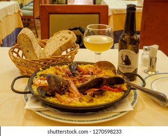 Santiago de Compostela, Galicia, Spain - October 4, 2014: Seafood paella with Peregrina beer is the well-deserved dinner of an exhausted but happy pilgrim