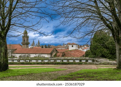 Santiago de Compostela in Galicia, Spain, framed by a historic cemetery wall and a prominent bell tower. The red-tiled roofs of ancient buildings, combined with the cathedral spires in the background - Powered by Shutterstock