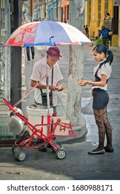 Santiago De Cuba, Cuba - 01/14/2017: Old Man Selling Food On The Street To A Young Woman