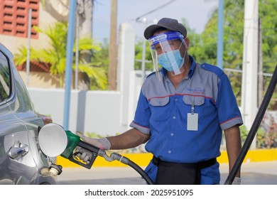 Santo Domingo, Dominican Republic - October 15, 2020 - Working Man Wearing Covid Protection Mask Looks At Camera, Fills Up Gas For Customer