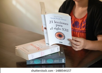 SANTO DOMINGO/DOMINICAN REPUBLIC - AUGUST 23, 2019: Woman reads Yuval Noah Harari best seller "21 Lessons for the 21st Century" (Spanish Edition) on a table with other books from the same author.