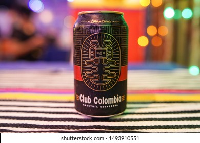 SANTO DOMINGO/DOMINICAN REPUBLIC - AUGUST 30, 2019: Club Colombia premium black lager beer can over a tablecloth with Colombian flag colors and colorful bokeh background.