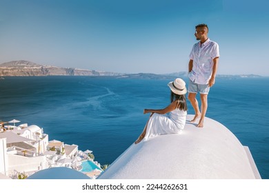 Santorini Greece, a young couple on luxury vacation at the Island of Santorini watching the sunrise by the blue dome church and whitewashed village of Oia Santorini, Asian women and caucasian men  - Powered by Shutterstock