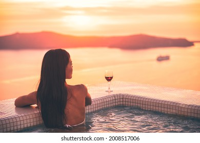 Santorini Luxury Vacation Woman Relaxing Swimming Hot Tub Pool At Sunset. Wellness Spa Retreat High End Fancy Lifestyle Honeymoon Destination.