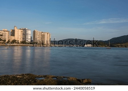 Santos city, Brazil. Waterfront buildings reflected in the sea water of the beach in the neighborhood of Ponta da Praia. In the background, the fortress of Barra.