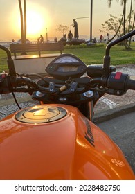 Santos, São Paulo - Brazil - August 20, 2021: Front partial view of an orange motorcycle brand Kawasaki, model Er6n. Stop in the Ponta da Praia region at sunset.