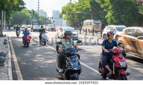 Sanya, Hainan island, China - May 15, 2019: Road\
traffic. A lot of electric cars. Hybrid buses. 90 percent of mopeds\
are electric. From 2030, only electric transport will be allowed on\
the island.