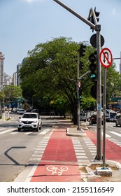 SAO PAULO - BRAZIL - SEP 27, 2021: The red bicycle lane markings painted on the asphalt of Antartica avenue, at the crossing with Padre Antonio Tomas street under sunny clear blue sky.