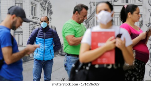 Sao Paulo, SP / Brazil - April 15, 2020: People With Face Masks Stand In A Line Together With People Without It In Front Of Caixa Economica Federal Bank During The Coronavirus Outbreak, COVID-19.