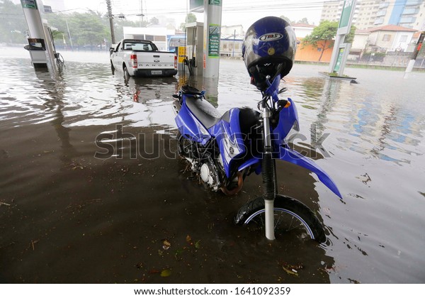 Sao Paulo, SP / Brazil - March 18, 2014: A\
motorcycle and a car are seen stuck at a gas station in a flooded\
avenue during heavy rains.