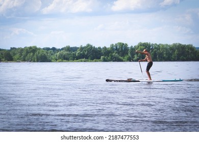 Sap Surfing. Surf Training. Men, Friends Ride SUP Boards On A Big River During Sunrise.