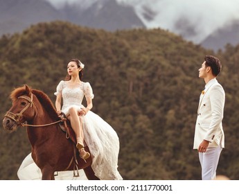 Sapa city, Vietnam - February 2021: The bride and groom take a wedding photo with a powerful horse. Beautiful wedding photo of a happy couple