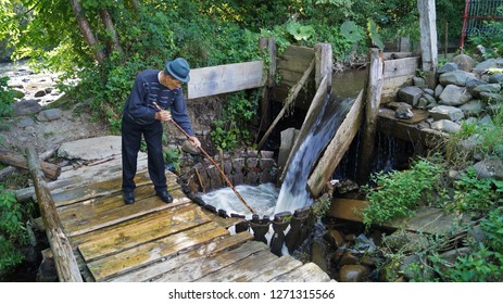 Sapanta, Romania - July 24, 2014: Old Man Doing The Laundry The Traditional Way In Maramures Country In Cold Water Coming From The River Showing Man Do Household Also In More Traditional Societies.