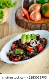 Sapi lada hitam, Indonesian and Chinese cuisine, stir fried beef with black pepper sauce and red bell peppers in white plate on wooden table.