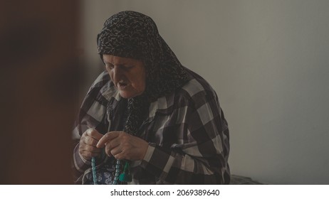 Sarajevo, Bosnia and Herzegovina 4 November, 2021: Old mature muslim hijab woman doing zikr with tesbih or rosary beads after salah pray at home, islam concept