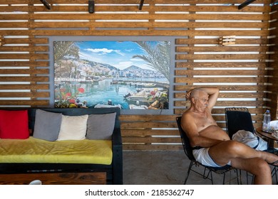 Saranda, Albania July 31, 2022 A Senior Man Sits In A Beach Bar Relaxing.