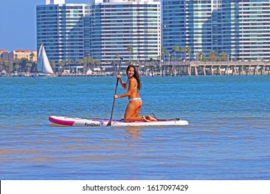 SARASOTA, FLORIDA - JANUARY 13, 2020: A Young Woman Kneeling While Rowing Her FunWater Paddle Board Out Into Sarasota Bay. Stand Up Paddle Boarding Is An Offshoot Of Surfing That Originated In Hawaii.