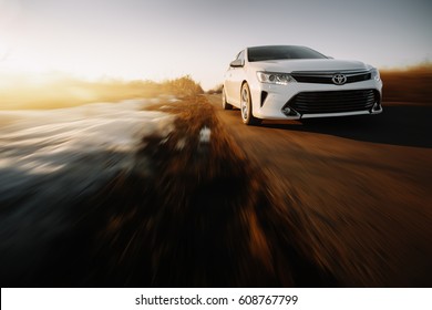 Saratov, Russia - March 15, 2017: White car Toyota Camry XV50 is driven at empty countryside asphalt road at sunset