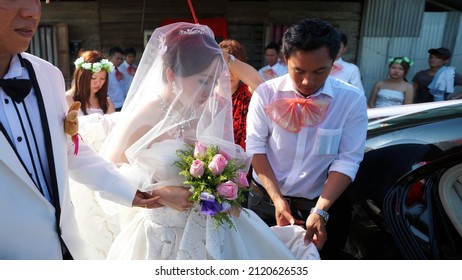 Sarawak, Malaysia – August 1, 2013: Portrait Of A Young Pretty Asian Bride In Formal Lace And Veil Wedding Dress Holding A Beautiful Wedding Bouquet Walking Into The Car.