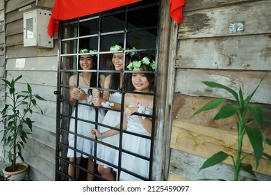Sarawak, Malaysia – August 31, 2013: The photo showing portrait of a group of pretty Asian girls or bridesmaids excited to waiting at gate or door and looking outside for the groom's brothers to come.