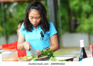 Sarawak, Malaysia – December 28, 2012:The Photo Showing An Asian Young Woman Chopping Vegetables On A Wooden Board At Outdoor.                            