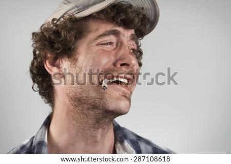 Sarcastic redneck laughs hysterically while smoking a cigarette