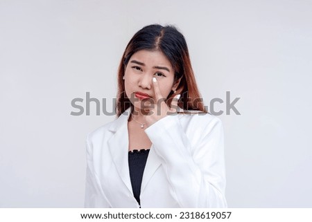 A sarcastic young woman pulling her lower eyelid with a finger to mock someone. Making fake tears to taunt. Isolated on a white background.