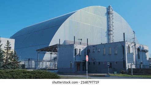 Sarcophagus over the destroyed reactor of the Chernobyl nuclear power plant. Giant metal hangar, radiation protection. No people, windy weather.