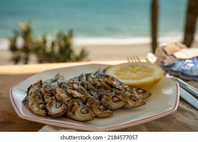 Sardines espeto prepared on skewers and open flame on fireplace with olive trees wood, served outdoor with and view on blue sea, Malaga, Andalusia, summer vacation in Spain - Powered by Shutterstock