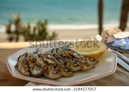 Sardines espeto prepared on skewers and open flame on fireplace with olive trees wood, served outdoor with and view on blue sea, Malaga, Andalusia, summer vacation in Spain
