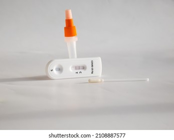 SARS-CoV-2 Antigen Rapid Test (Nasal Swab) For Self Testing With Used Sterile Swab And Test Cassette With Positive Result Isolated On White In Bright Sunlight. COVID-19 Ag.