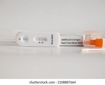 SARS-CoV-2 Antigen Rapid Test (Nasal Swab) For Self Testing With Used Sterile Swab And Test Cassette With Positive Result Isolated On White In Bright Sunlight. COVID-19 Ag.