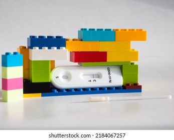 SARS-CoV-2 Antigen Rapid Test (Nasal Swab) for self testing with a swab and test cassette with Negative result between interlocking toy bricks on white. COVID-19 Ag. Concept of pandemic in childhood