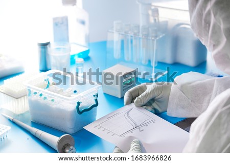 SARS-COV-2 nucleic acids diagnostics kit. Epidemiologist in protective suit, mask and glasses performs and analyzes results of pcr tests detecting SARS-nCoV-2 virus, cause of Covid-19 viral pneumonia.