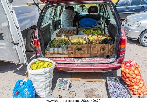 Sarvoda, Sughd\
Province, Tajikistan. Vendor selling fruits and vegetables out of\
their car at the market in\
Sarvoda.