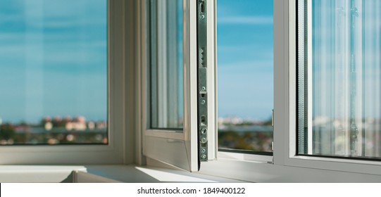 Sash plastic balcony window. The frame is white,the sash is slightly open. The sun's rays through the glass