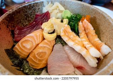 Sashimi Don; raw slices of Tuna, Salmon, Mackerel, together with Shrimps, Sea Urchin Roe, Seaweed and Ginger, on top of hot rice. Some Wasabi paste. Simple and healthy meal as a catering concept. - Shutterstock ID 2205797955